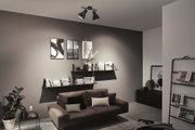 Modern living room with black metal ceiling light, grey wall, and brown sofa with cushions