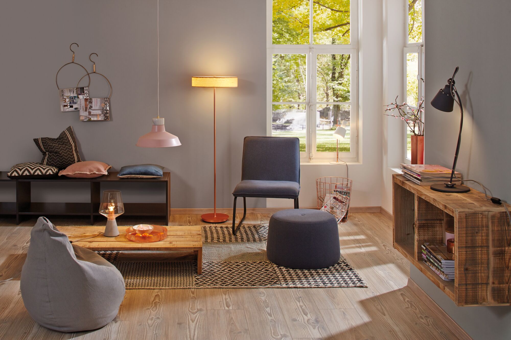 Cozy living room with grey bean bag, blue chair and ottoman, wooden shelf and warm lighting fixtures