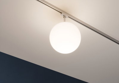 Runde weiße Deckenleuchte aus Glas an Schienensystem mit warmweißem Licht für Wohnräume