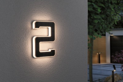 Oplyst husnummer 2 i sort materiale med varmt hvidt LED-lys på grå udvendig væg
