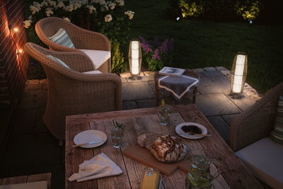 Cozy patio with rattan furniture and warm white LED outdoor lights for atmospheric garden lighting.