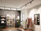 Dressing moderne avec éclairage sur rail noir et portant à vêtements sous lumière chaude