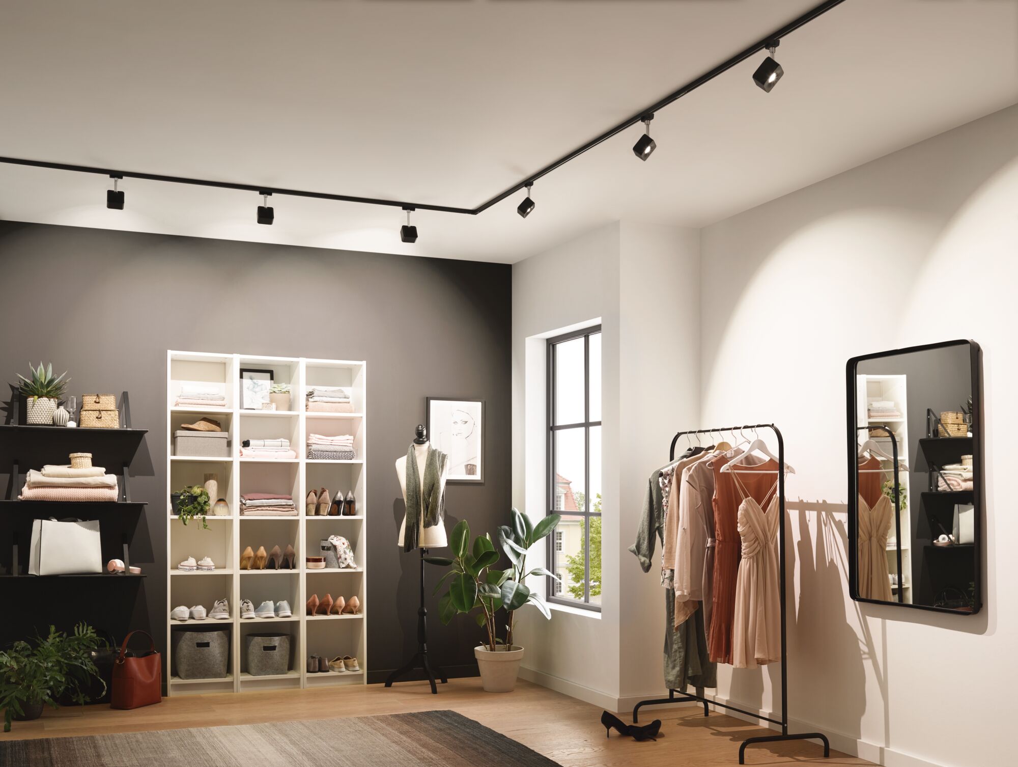 Modern dressing room with black track lighting and clothing rack with dresses under warm lighting