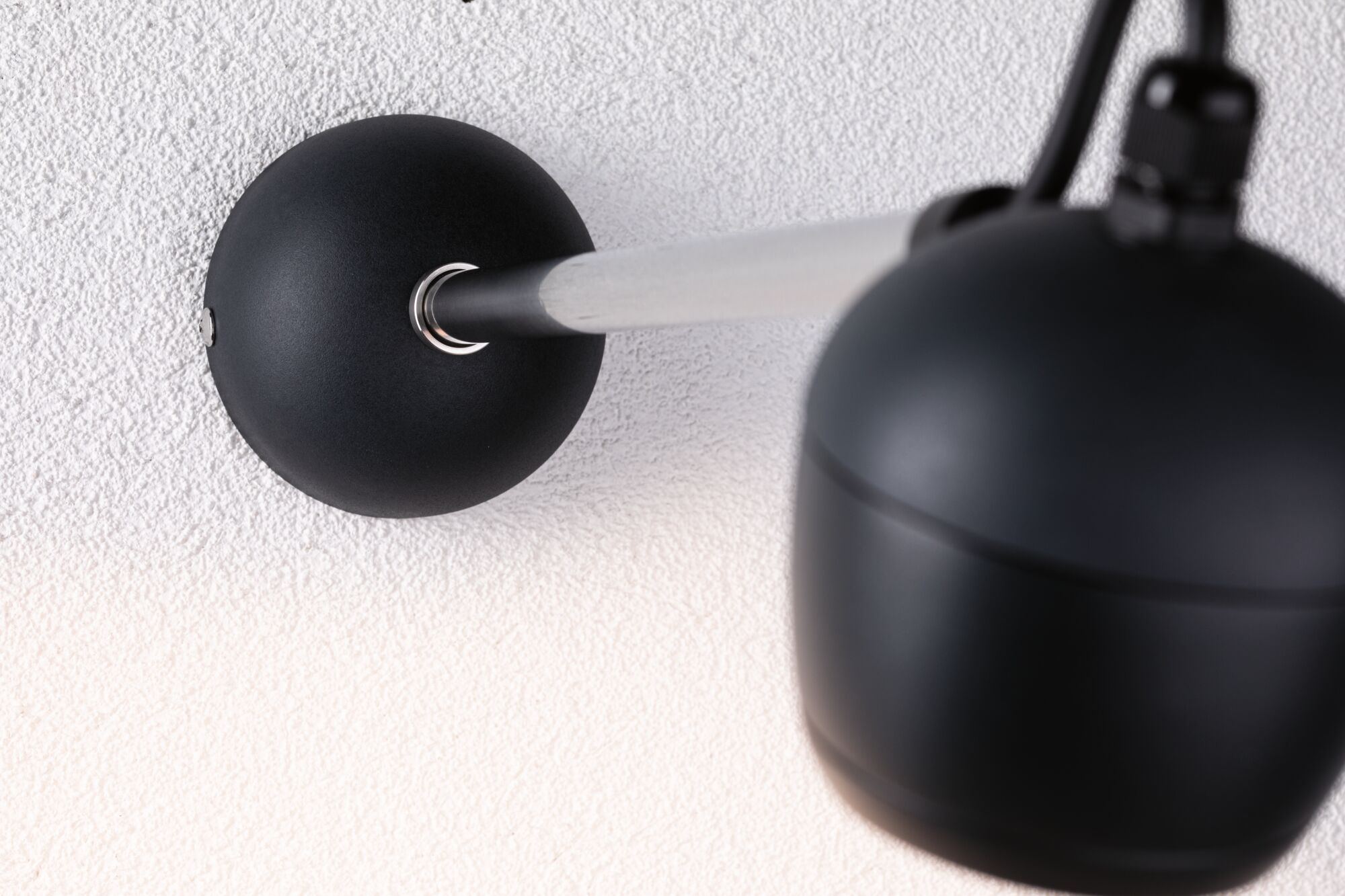Schwarze Wandlampe mit mattem Metallarm und kugelförmiger Leuchte an weißer Wand für moderne Beleuchtung