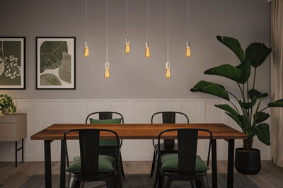 Modern dining area with wooden table, black metal chairs, and warm LED pendant lights for home lighting