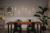 Modern dining area with wooden table, black metal chairs, and warm LED pendant lights for home lighting