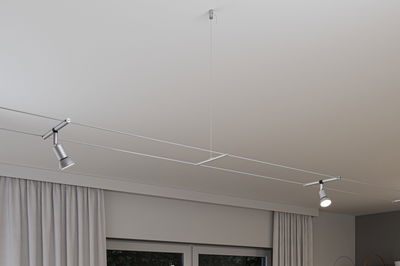Modern silver cable lighting system with two adjustable LED spotlights on white ceiling for living room