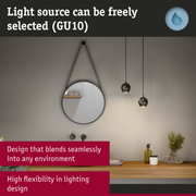 Black metal pendant lights above wooden shelf with round mirror and bathroom accessories