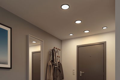 Flache runde LED-Deckenleuchten mit schwarzem Rahmen in modernem Flur mit Garderobe und Spiegel.
