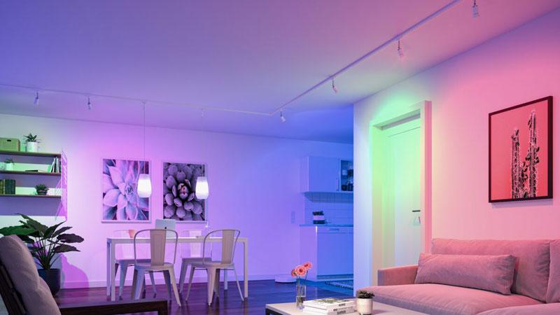Moderne woonkamer met kleurveranderende LED-plafondverlichting en minimalistisch wit en houten meubilair.