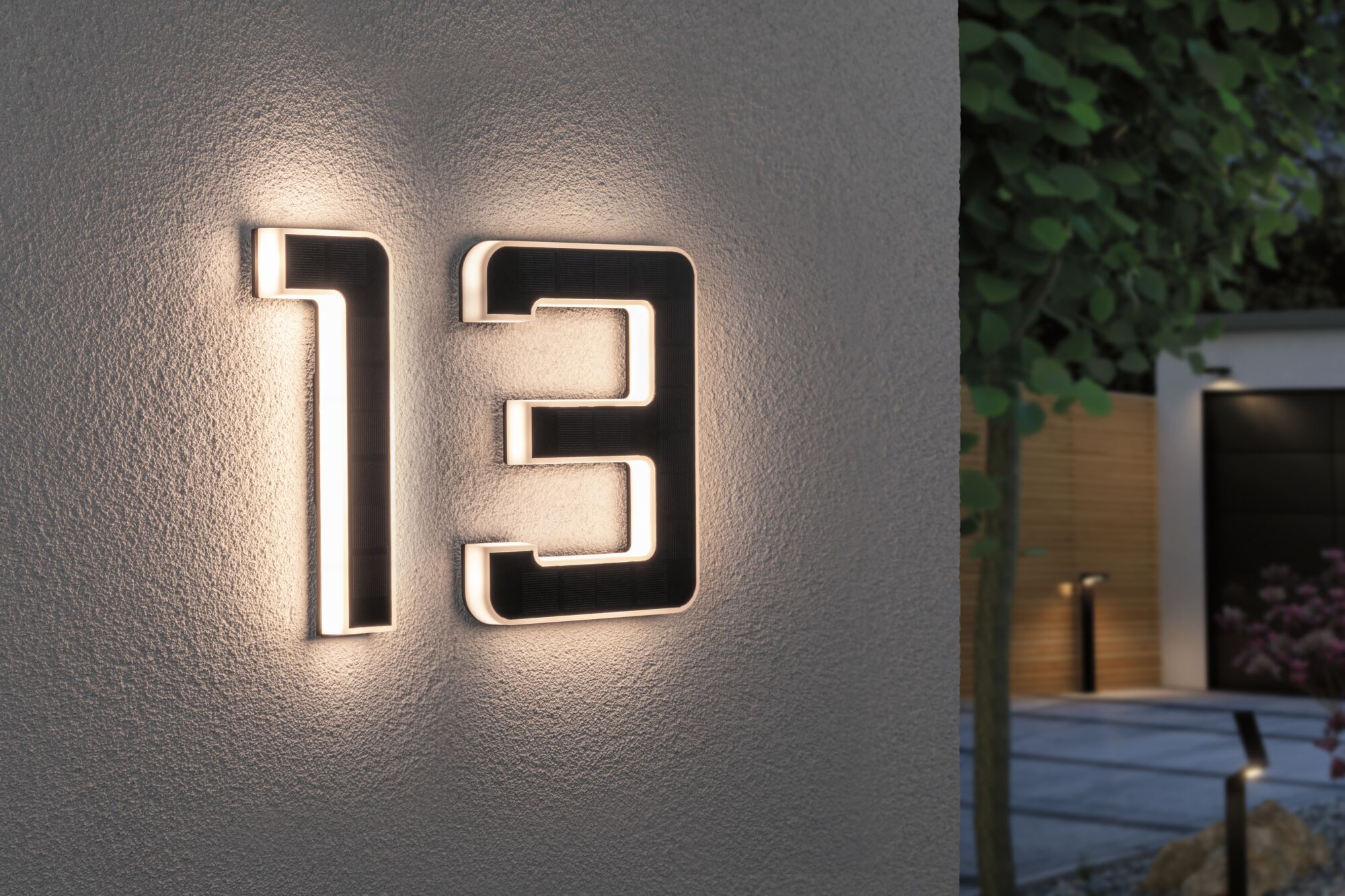 Modern house number 13 in black material with integrated LED lighting on exterior wall.