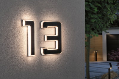 Modern house number 13 in black material with integrated LED lighting on exterior wall.