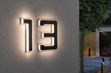 Modern house number 13 in black material with integrated LED lighting on exterior wall.