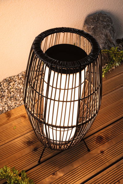 Modern black metal wire lamp with white light body on wooden terrace for outdoor lighting