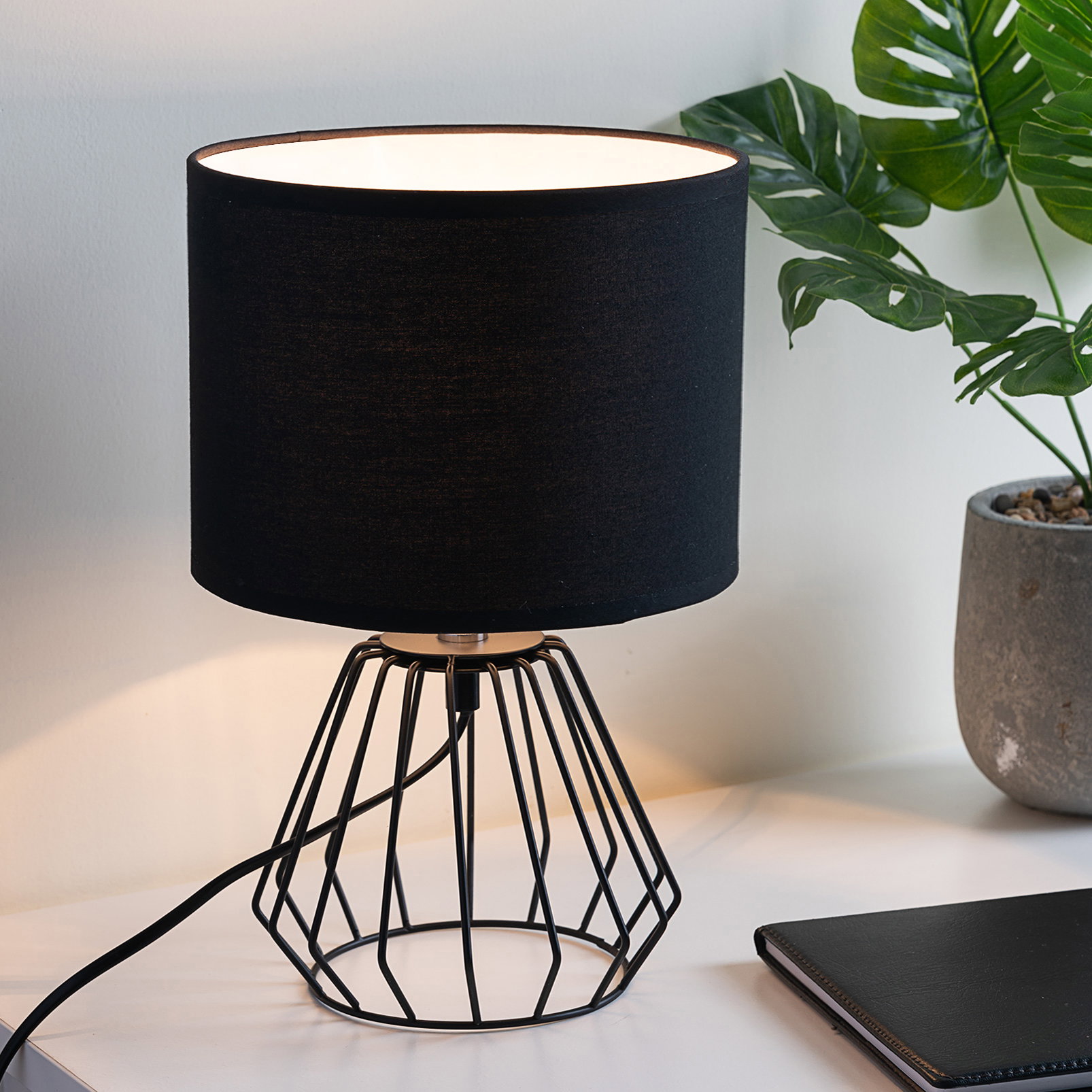 Moderne Tischlampe mit schwarzem Stoffschirm und geometrischem Metallgestell für stilvolle Raumbeleuchtung