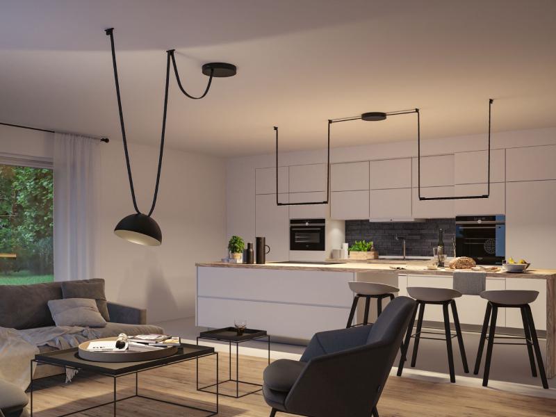 Modern living room with black metal pendant light and open kitchen featuring bar stools and wooden countertop.
