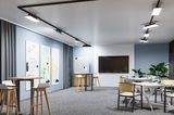 Modernes Büro mit schwarzen LED-Schienenstrahlern an der Decke und multifunktionalen Möbeln in hellem Design.