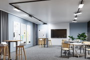 Modernes Büro mit schwarzen LED-Schienenleuchten an der Decke und hellblauen Wänden