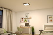 Quadratische Deckenleuchte in Schwarz mit warmweißem Licht in modernem Schlafzimmer mit Schreibtisch.