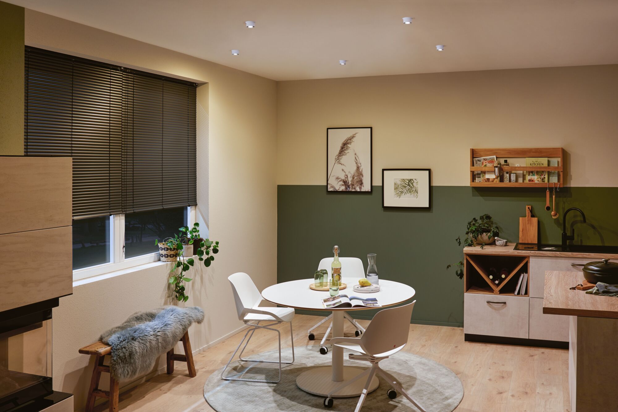 Moderne Küche mit weißen Möbeln, Holzregal und grüner Wandfarbe, LED-Deckenstrahler beleuchten den Raum