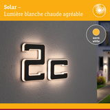 Numéro solaire 2c en matériau noir avec lumière LED blanc chaud sur mur gris