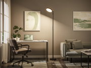 Schwarze Stehleuchte mit rundem LED-Leuchtkopf in modernem Wohnzimmer mit Arbeitsplatz und Sofa