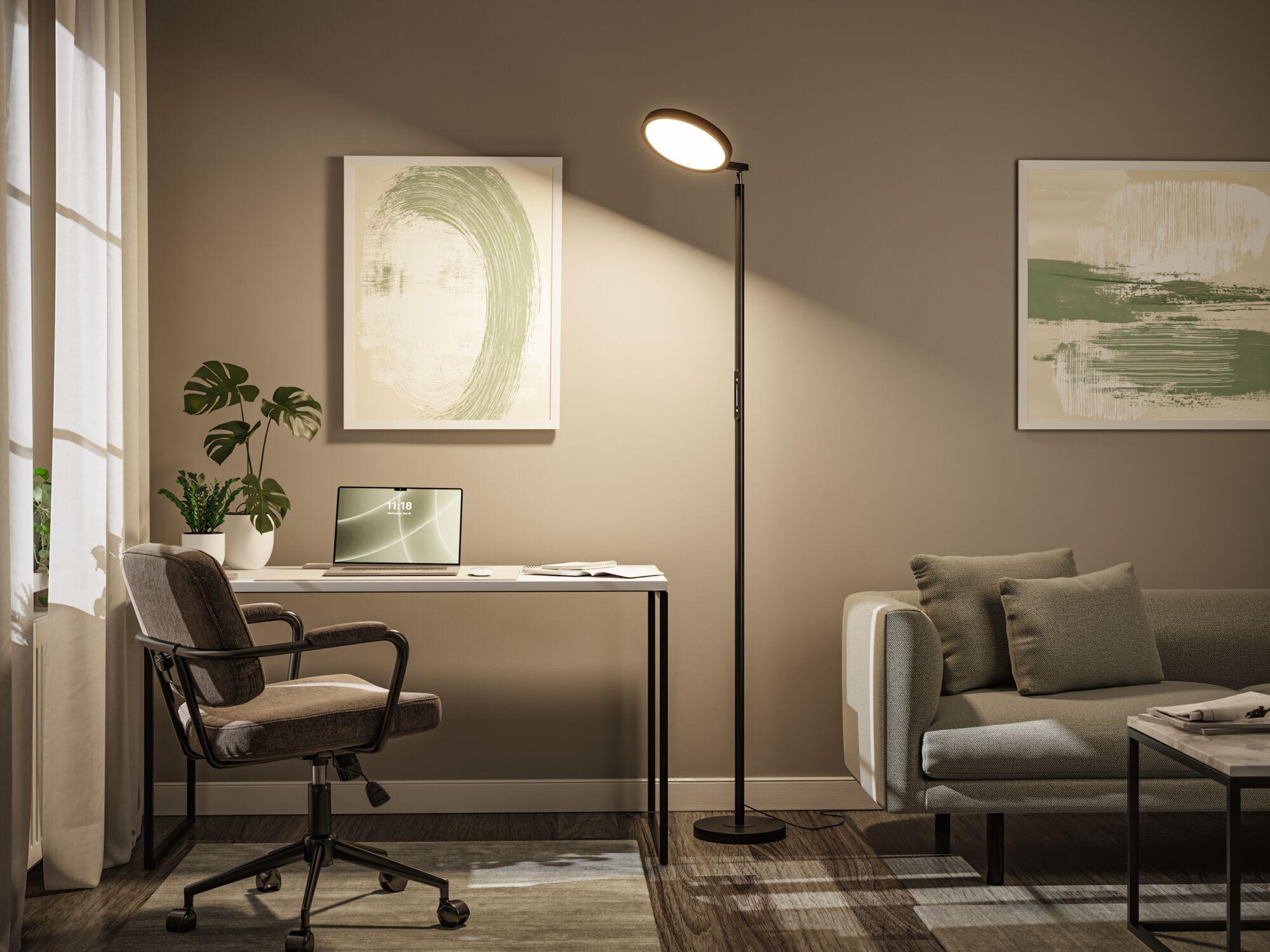 Schwarze Stehleuchte mit rundem LED-Leuchtkopf in modernem Wohnzimmer mit Arbeitsplatz und Sofa