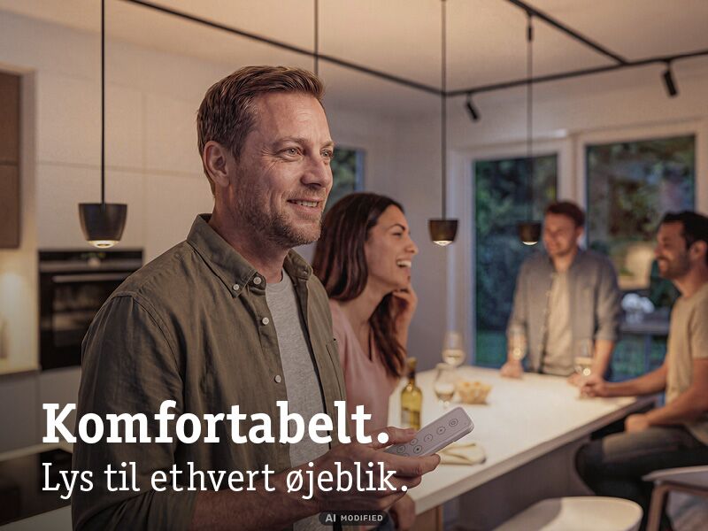 Mand med fjernbetjening styrer moderne LED-pendellamper i hyggeligt køkken med venner.