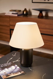 Moderne Tischlampe mit schwarzem Keramikfuß und cremefarbenem Stoffschirm auf Marmor-Tisch