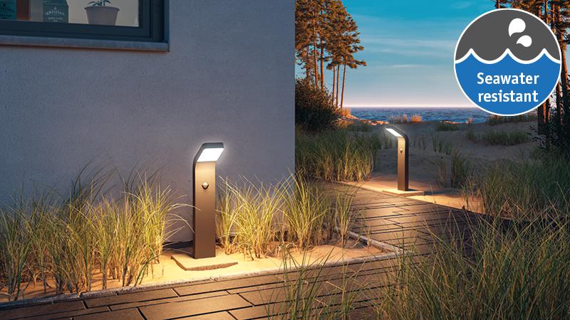 Moderne schwarze Außenleuchte mit warmweißem LED-Licht am Weg, seewasserresistent für Gartenbeleuchtung.