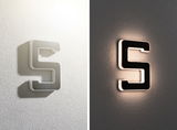 Applique murale LED moderne en forme de S avec finition noire et blanche, éclairage décoratif intérieur.