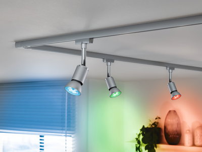 Drei silberne LED-Strahler an Schienensystem mit blauem, grünem und rotem Licht für Wohnraumbeleuchtung