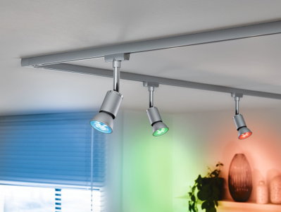 Drei silberne LED-Strahler an Schienensystem mit blauem, grünem und rotem Licht für Wohnraumbeleuchtung