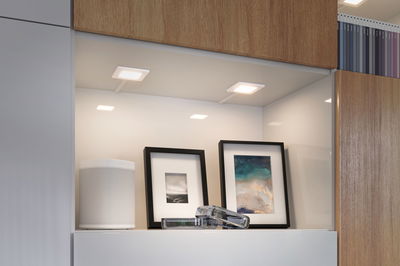 Modern white LED under-cabinet lights in kitchen shelf with speaker and picture frames for accent lighting