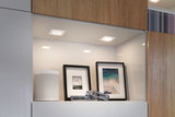 Modern white LED under-cabinet lights in kitchen shelf with speaker and picture frames for accent lighting