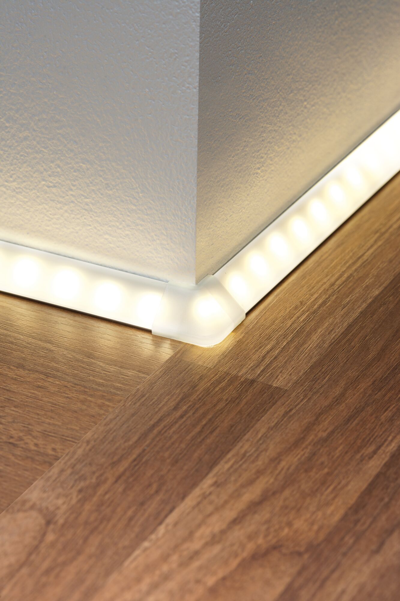 Weiße LED-Eckleuchte mit warmweißem Licht auf Holzfußboden für moderne Raumbeleuchtung