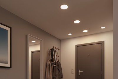 Flat white LED recessed lights in ceiling of modern hallway with gray door and coat rack
