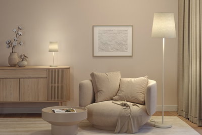 Beige vloerlamp en tafellamp met stoffen kap in moderne woonkamer met fauteuil en houten dressoir