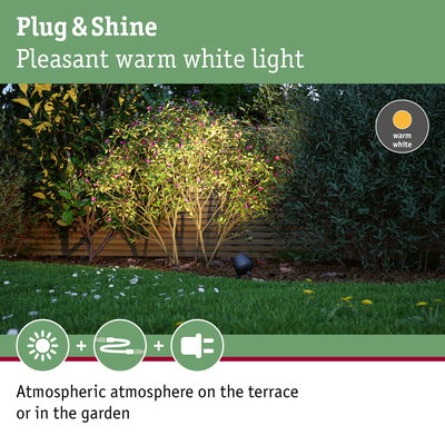 Outdoor spotlight with warm white light illuminating green bushes for atmospheric garden terrace lighting.