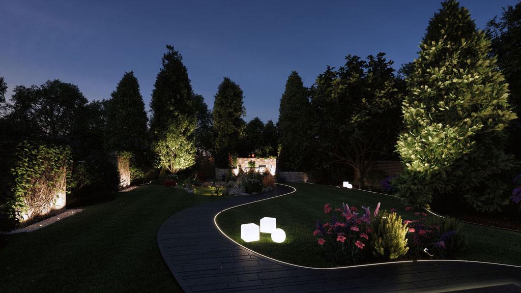 Havegang med LED-belysning og oplyste træer til stemningsfuld udendørsbelysning.