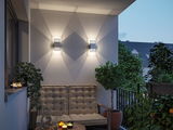 Modern outdoor balcony with two white metal wall lights casting decorative illumination in evening