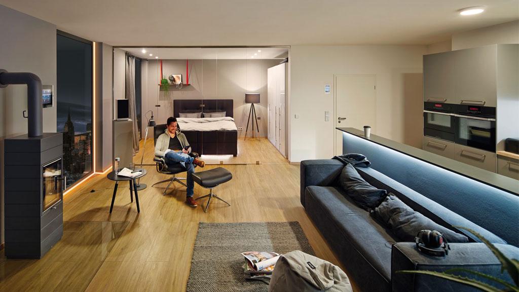 Modernes Wohnzimmer mit Holzfußboden, grauem Sofa, Kamin und indirekter LED-Beleuchtung für gemütliche Atmosphäre