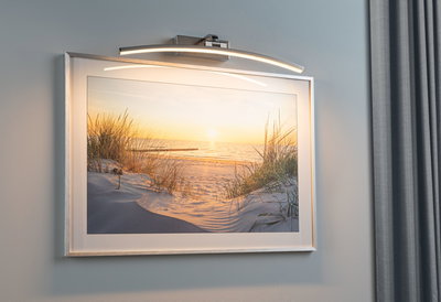 Modern LED picture light in brushed metal with curved lamp bar for wall art and photos.