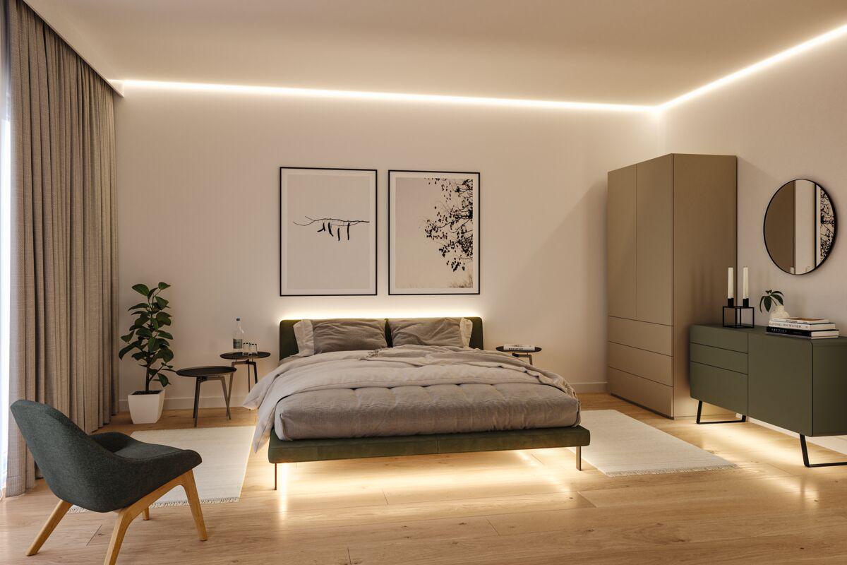 Modern bedroom with LED strip lighting, green fabric bed, and minimalist wooden furniture in warm tones