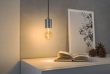 Modern LED pendant lamp with grey metal socket above white table with book and decor items.