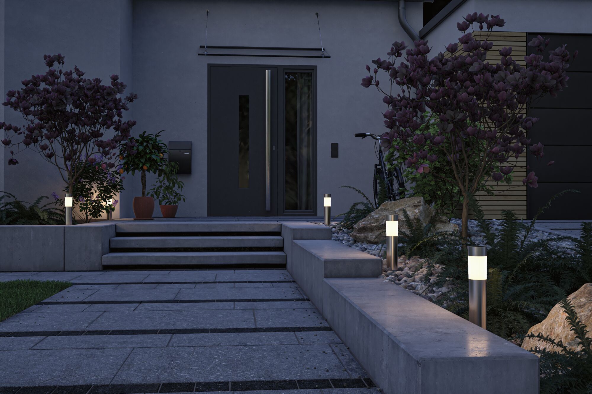 Éclairage extérieur moderne avec lampes de chemin en acier inoxydable et lumière blanche chaude à l'entrée en béton gris.