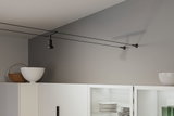 Lustre de plafond à câble noir avec spot dans une cuisine moderne avec armoires blanches et vaisselle empilée