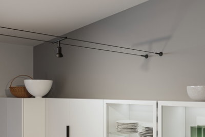 Lustre de plafond à câble noir avec spot dans une cuisine moderne avec armoires blanches et vaisselle empilée