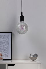 Hanging light bulb with silver mosaic glass surface and black cable against white wall.
