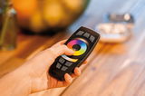 Main tenant une télécommande noire Paulmann avec roue tactile colorée pour contrôle LED